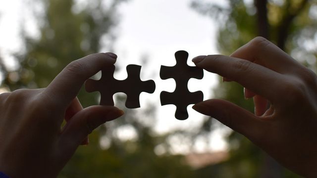 Hands fitting puzzle pieces together